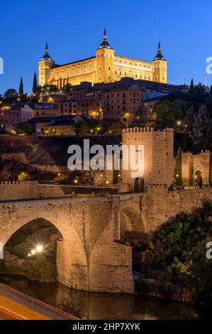 Toledo a Dusk - veduta verticale del tramonto della città storica di Toledo a Puente de Alcántara, con la fortezza di Alcázar in cima alla collina. Toledo, Spagna. Foto Stock