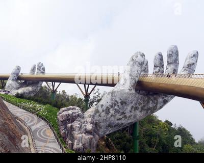 Da Nang, Vietnam - 12 aprile 2021: Golden Bridge sollevato da mani giganti in Ba Na Hills, un famoso parco a tema e resort nel Vietnam centrale Foto Stock