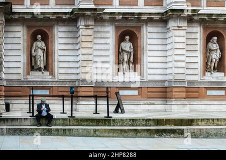 Statue presso la Royal Academy of the Arts di Londra guardando giù un uomo che fa una telefonata mobile. Foto Stock