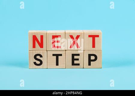 Next Step Concept con lettere alfabetiche su cubi di legno Education e business startup concept. Le parole Next Step su piccoli dadi di legno, Blu Foto Stock