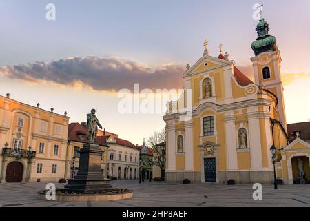 La storica piazza besi kapu a Gyor con la chiesa in Ungheria tramonto. Foto Stock