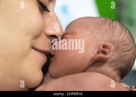 ritratto di una madre amorevole con il suo neonato. La mamma sorride alla figlia mentre avvicinano i loro volti al tocco. Concetto affetto e cura in Foto Stock