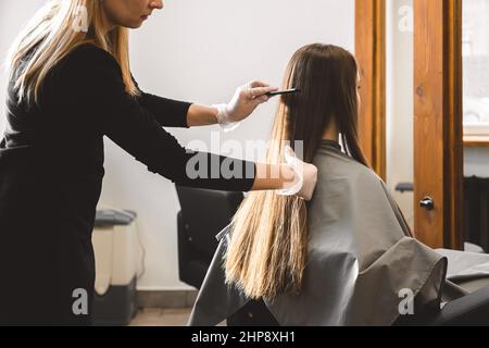 Master parrucchiere pettina i capelli della ragazza dopo il lavaggio e prima di styling in un salone di bellezza. Foto Stock