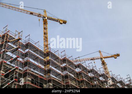 nuovo progetto di costruzione con ponteggi di grandi dimensioni e due gru Foto Stock