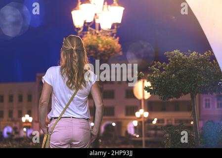 Donna alla moda nella città notturna. Bella giovane donna in piedi in strada nella città notturna. Passeggiata nella città vecchia europea Foto Stock