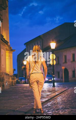 Donna alla moda nella città notturna. Bella giovane donna in piedi in strada nella città notturna. Passeggiata nella città vecchia europea Foto Stock