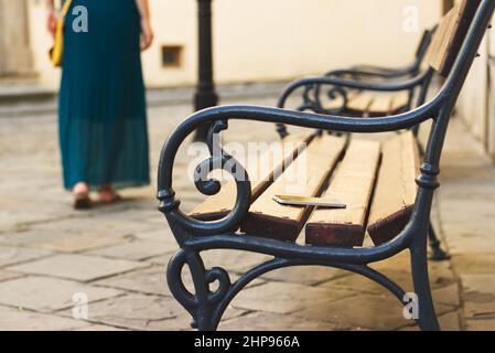 Smartphone dimenticato sulla panca in città. La donna sta lasciando da una panca dove ha perso il suo telefono cellulare. Foto Stock