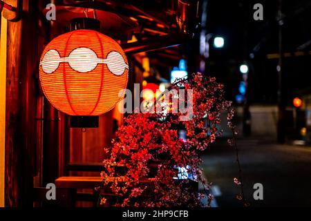 Kyoto, Giappone strada strada strada strada strada colorata vicolo nel quartiere di Gion di notte con primo piano di illuminazione tradizionale lampada di carta rossa lanterna e ciliegio bl Foto Stock