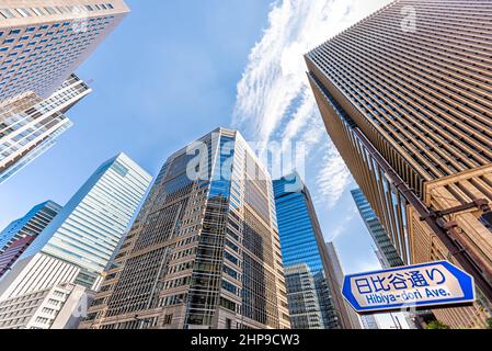 Tokyo, Japan Road insegne in inglese per hibiya-dori avenue grattacieli vista ad angolo basso che si affaccia sullo skyline cittadino nel centro cittadino giapponese Chiyoda città Foto Stock