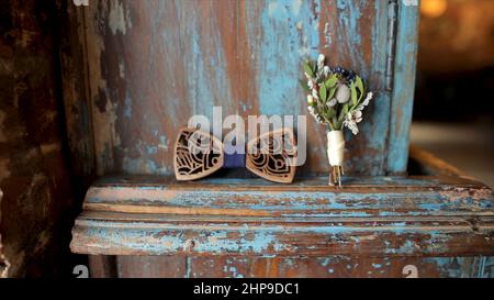 Elegante arco blu e boutonniere su sfondo di legno. Buon umore che si prepara la mattina prima del matrimonio. Cravatta ad arco in legno e boutonniere con grunge b Foto Stock