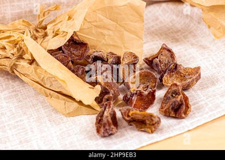Tradizionale hoshigaki giapponese essiccato fette di merenda di frutta in carta da imballaggio su sfondo chiaro. Foto Stock
