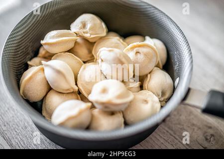 Pentola di cottura con gnocchi russi tradizionali congelati pelmeni ripieni di carne per bollire macro closeup Foto Stock