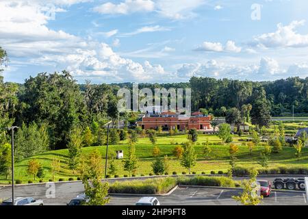 Vista ad angolo alto del paesaggio estivo in Alachua, Florida vicino a Gainesville con parcheggio auto edificio e alberi verdi con cielo blu Foto Stock