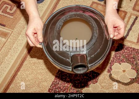 Il processo di pulizia della moquette con un aspirapolvere e un filtro dell'acqua. Contenitore dell'aspirapolvere con acqua sporca dopo la pulizia. Foto Stock