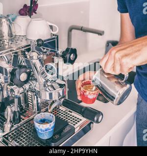 Preparare il caffè a casa con la macchina per espresso versando il latte evaporato in una tazza. Cucina stile di vita colazione. Ritaglio quadrato Foto Stock
