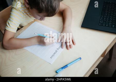 Uno scolaro che fa una lezione di matematica seduto alla scrivania nella stanza dei bambini Foto Stock