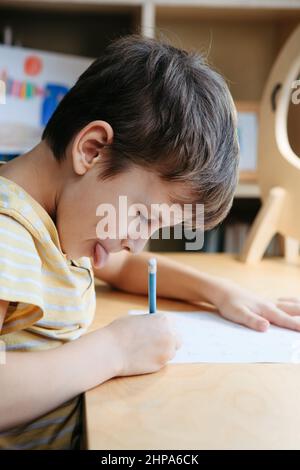 Uno scolaro che fa una lezione di matematica seduto alla scrivania nella stanza dei bambini Foto Stock