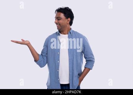 Uomo che tiene la mano a lato guardando a lato isolato. Uomo indiano Smoling. Commerciale, concetto di pubblicità Foto Stock