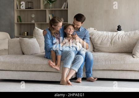 Felici genitori millenari che tengono in braccio il bambino allegro della figlia Foto Stock