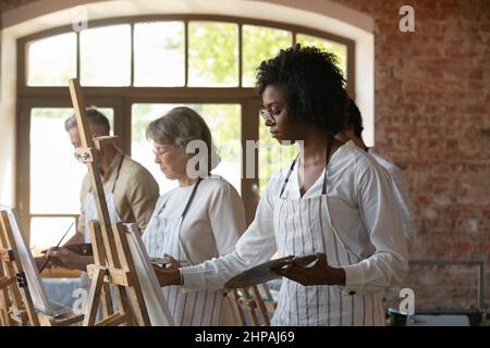 Donna americana africana concentrata millenaria che si disegna alla classe d'arte. Foto Stock