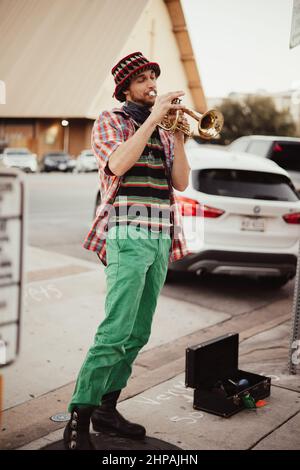 Colpo verticale di un giovane musicista maschile che suona la tromba per le strade di Austin, USA Foto Stock