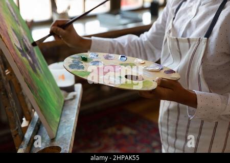 Primo piano ritagliato giovane artista maschile pittura su tela. Foto Stock