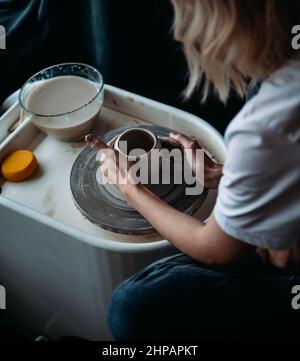 La ragazza lavora alla vista posteriore della ruota del vasaio Foto Stock