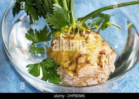 Tuber di sedano crudo con foglia in ciotola di vetro con acqua. Foto Stock