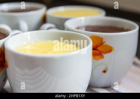 primo piano di bicchieri di porcellana riempiti di vaniglia gialla e di flummeria di cioccolato marrone Foto Stock