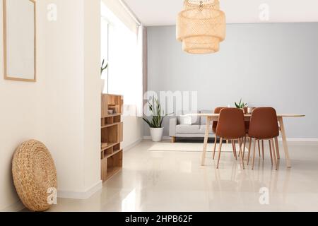 Interno della moderna sala da pranzo con tavolo, divano e lampada a sospensione Foto Stock