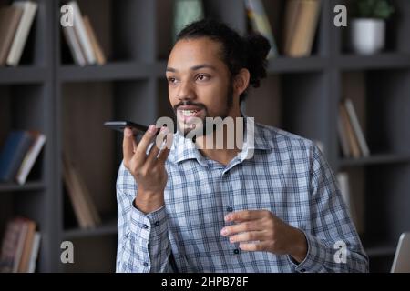 Felice affollato bel giovane africano americano uomo che registra il messaggio audio. Foto Stock