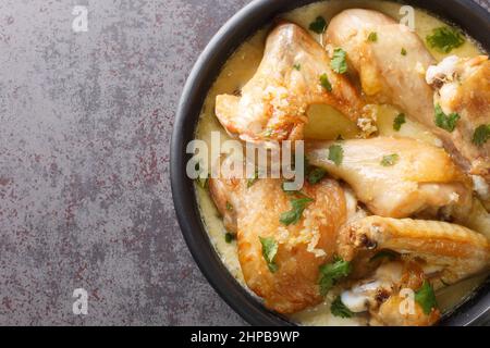 Shkmeruli è un piatto tradizionale caucasico georgiano di pollo in spicup salsa all'aglio nella pentola sul tavolo. Vista dall'alto orizzontale Foto Stock