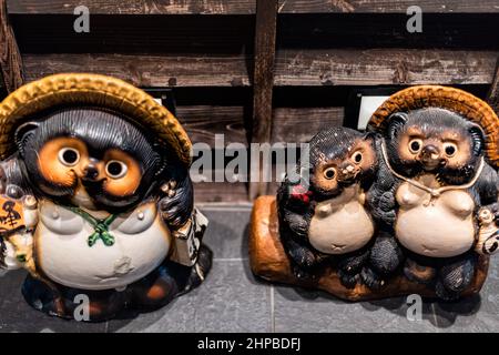 Osaka, Giappone - 13 aprile 2019: Osaka, Japan City Street di notte con statue sculture decorazione di Tanuki, un cane da racoon giapponese in tradizionale fo Foto Stock