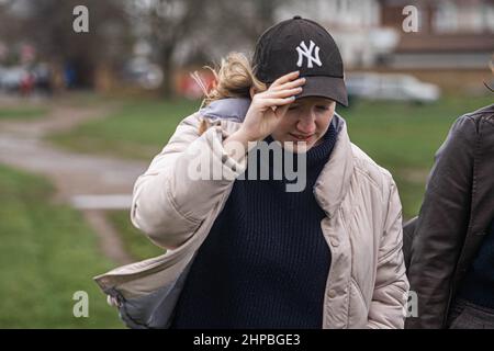 WIMBLEDON LONDRA, REGNO UNITO. 20 Febbraio, 2022. Una donna in un cappello di baseball lotta con le condizioni ventose su Wimbledon Common portato da Storm Eunice. Il Met Office ha emesso un avvertimento rosso per il sud e sud-ovest dell'Inghilterra, come gran parte del resto del Regno Unito è sotto ambra e giallo avvertimenti con venti fino a 100 mph, con pioggia e neve prevista.Credit: amer Ghazzal / Alamy Live News Foto Stock