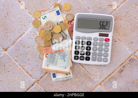 banconote e monete in euro giacenti su un tavolo con calcolatore Foto Stock