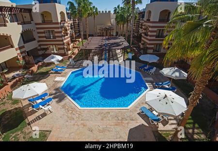 Vista aerea della piscina con edifici e lettini presso un lussuoso resort alberghiero tropicale Foto Stock