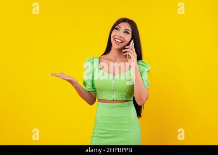 Signora allegra che parla sul cellulare allo studio giallo Foto Stock