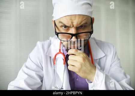 Un uomo con occhi incrociati sta guardando nel telaio. Malattia oculare. Il concetto di medico specialista pazzo. Vicino medico. Foto Stock