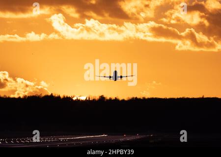 Aereo che decolla all'aeroporto di Stoccarda, contro il cielo dorato del tramonto con alcune nuvole Foto Stock