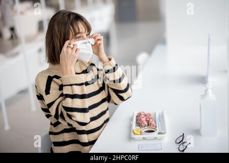 La donna toglie la maschera al ristorante Foto Stock