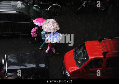 Mumbai; Maharashtra; India- Asia, giugno 2019 : immagine sfocata, vista aerea, tre ragazzi che camminano tenendo un ombrello sopra la testa sotto la pioggia pesante Foto Stock