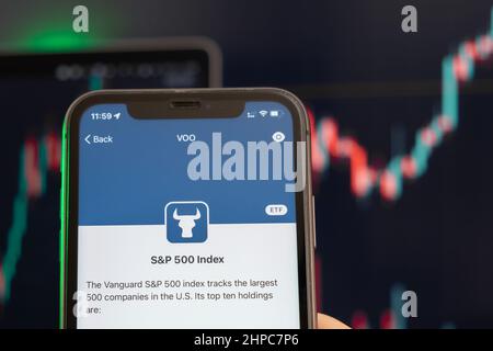 S e P 500 Indice del rialzo dei prezzi delle azioni con grafici sullo sfondo. L'uomo tiene uno smartphone con il logo sullo schermo, febbraio 2022, San Francisco, USA. Foto Stock