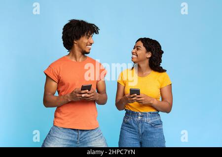 La coppia innamorata si guarda l'un l'altro, tenendo gli smartphone Foto Stock