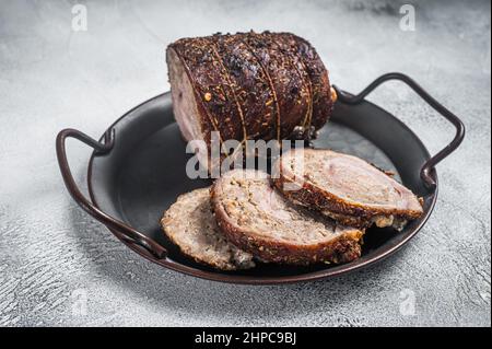 Involtini di carne di maiale arrosto affettati su un vassoio di acciaio. Sfondo bianco. Vista dall'alto Foto Stock