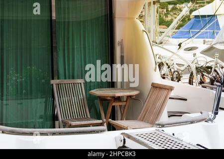 Tavolo e sedie in legno per un soggiorno confortevole su uno yacht sulla costa del mare. Area lounge su uno yacht. Gita in barca. Foto Stock