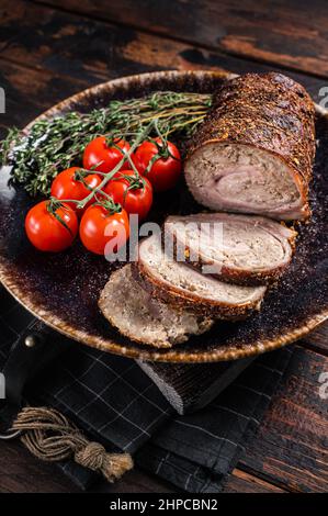 Involtini di maiale arrosto a fette - Porchetta su un piatto con spezie. Sfondo in legno. Vista dall'alto Foto Stock