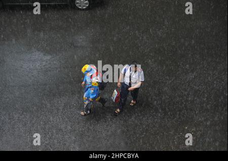 Mumbai; Maharashtra; India- Asia, giugno 2019 : immagine sfocata, vista aerea, fratello e sisterr che camminano sotto la pioggia pesante Foto Stock