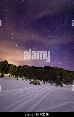 Piccolo rifugio di montagna nella neve in una notte di vino stellato Foto Stock