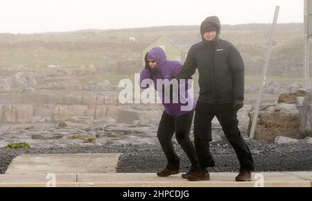 La gente affronta i venti alti a Doolin nella contea di Clare sulla costa occidentale dell'Irlanda. Data foto: Domenica 20 febbraio 2022. Foto Stock