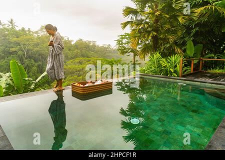 Donna che gusta la colazione galleggiante presso il resort di lusso a Bali Foto Stock